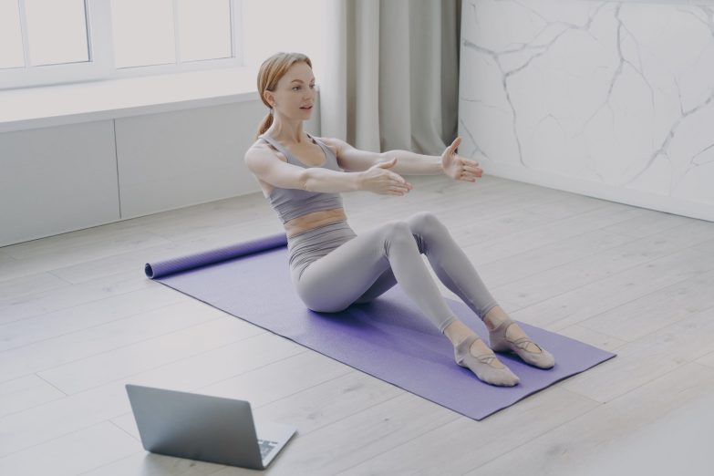 Press exercise and pilates at home. Video lessons on laptop. Concept of distance fitness classes.